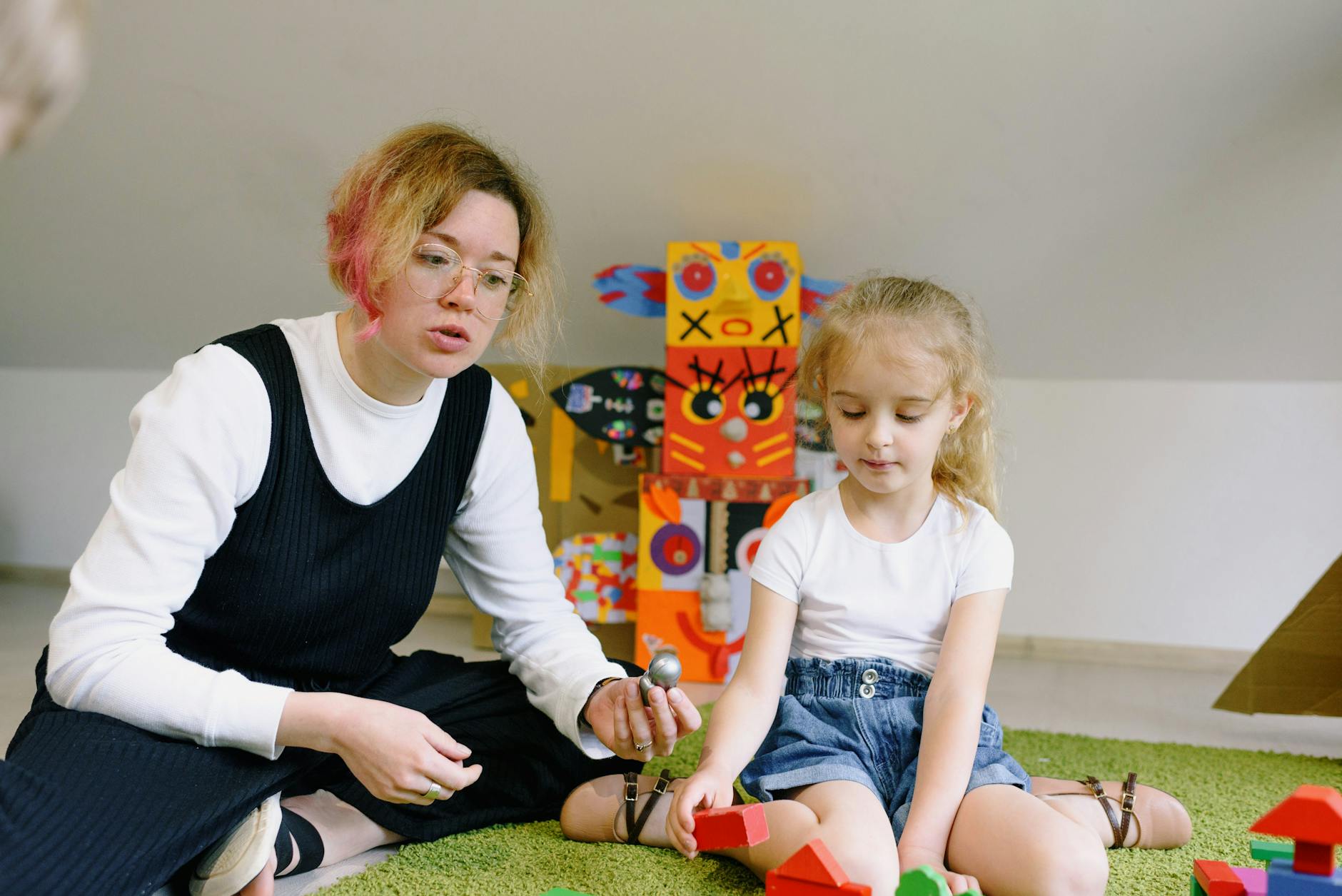Mama bawi się z dzieckiem kolorowymi klockami w sali zabaw Mama bawi się z dzieckiem kolorowymi klockami w sali zabaw